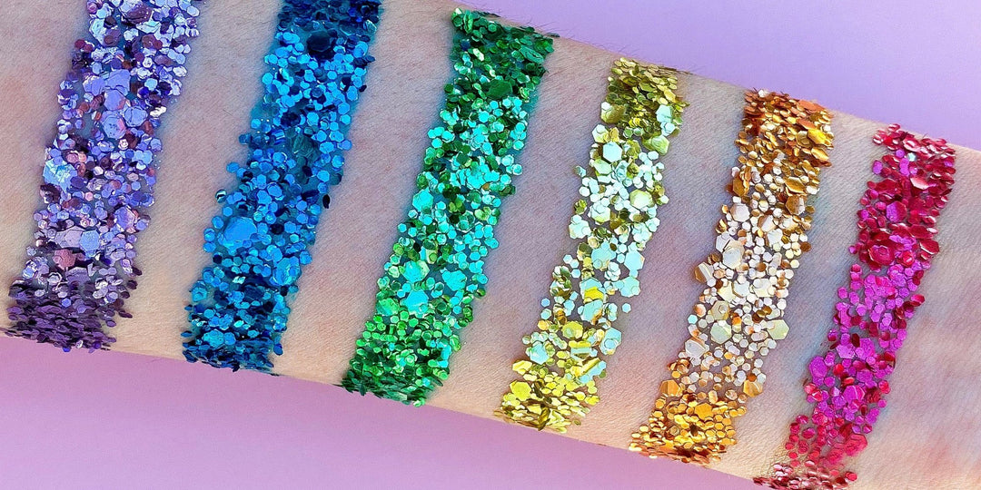 A swatch of rainbow eco glitters on a white forearm with a pink background