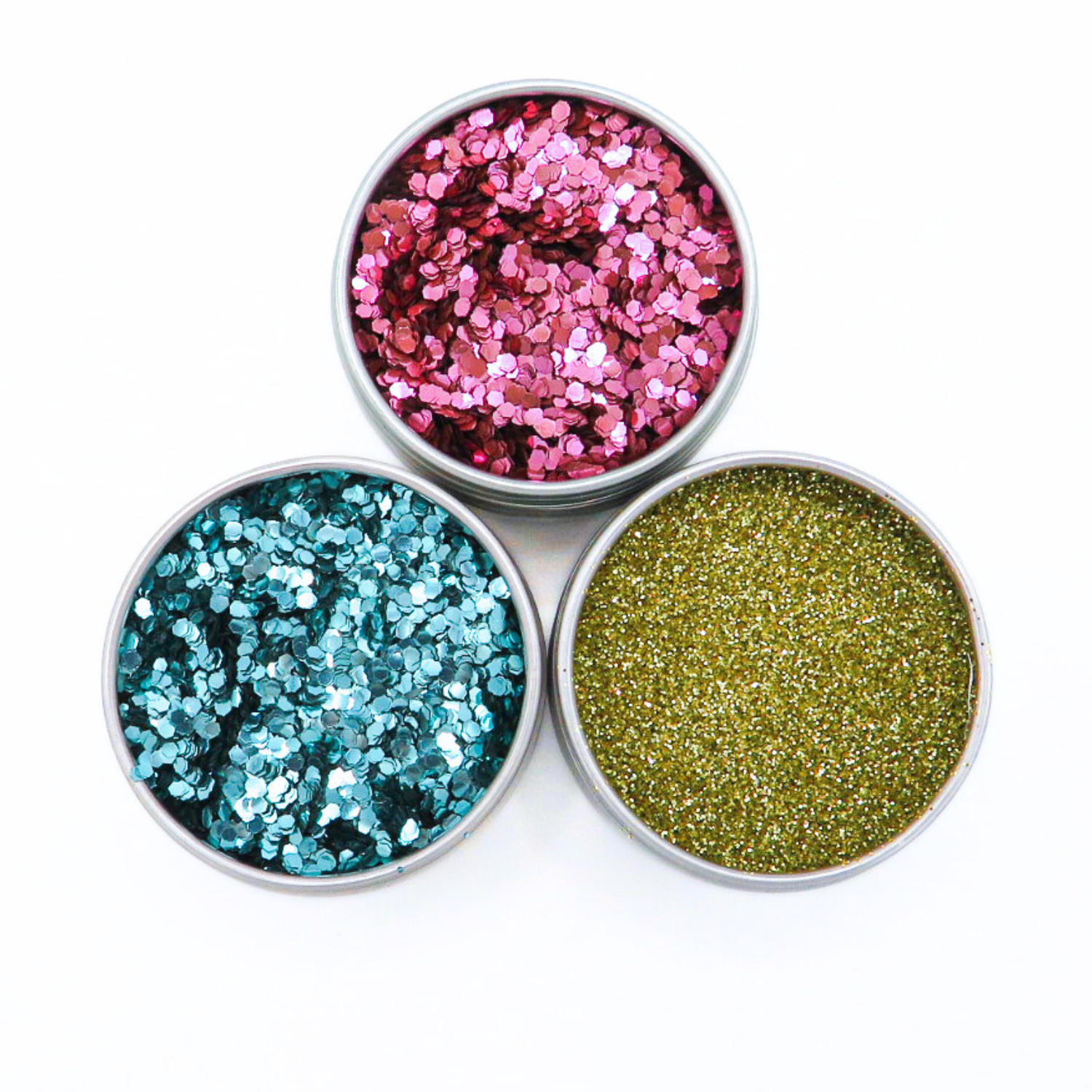 Three small round containers filled with colorful glitter on a white background