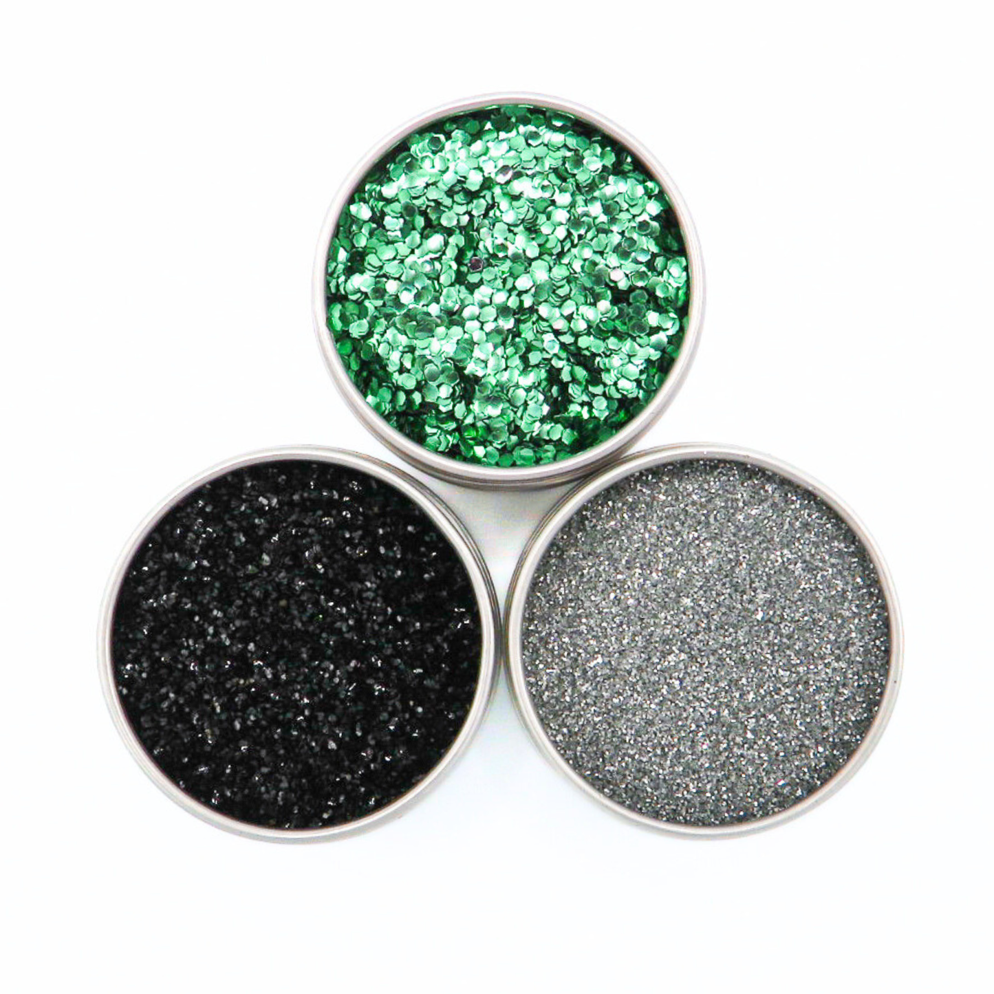 Three round containers of glitter in green, black, and gray on a white background