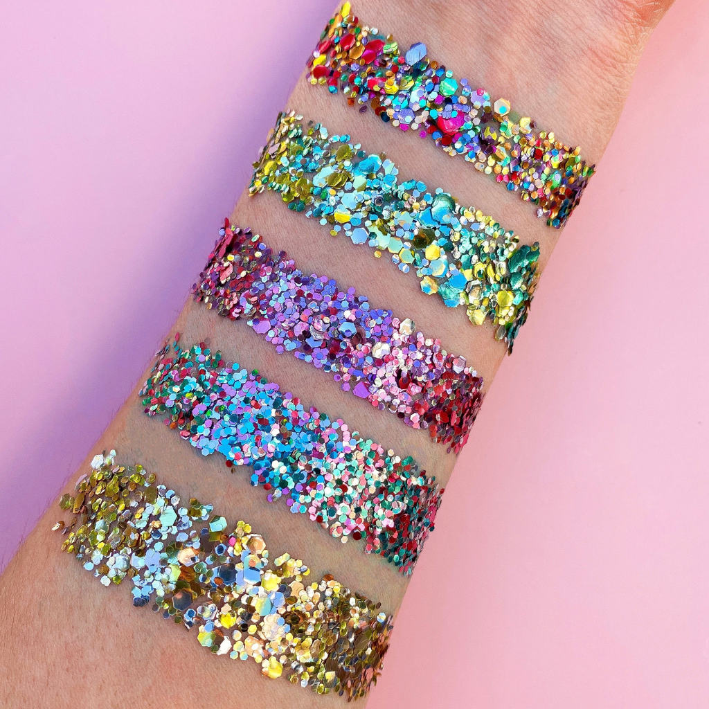 Eco glitter swatch of rainbow glitters on a forearm with a pink background