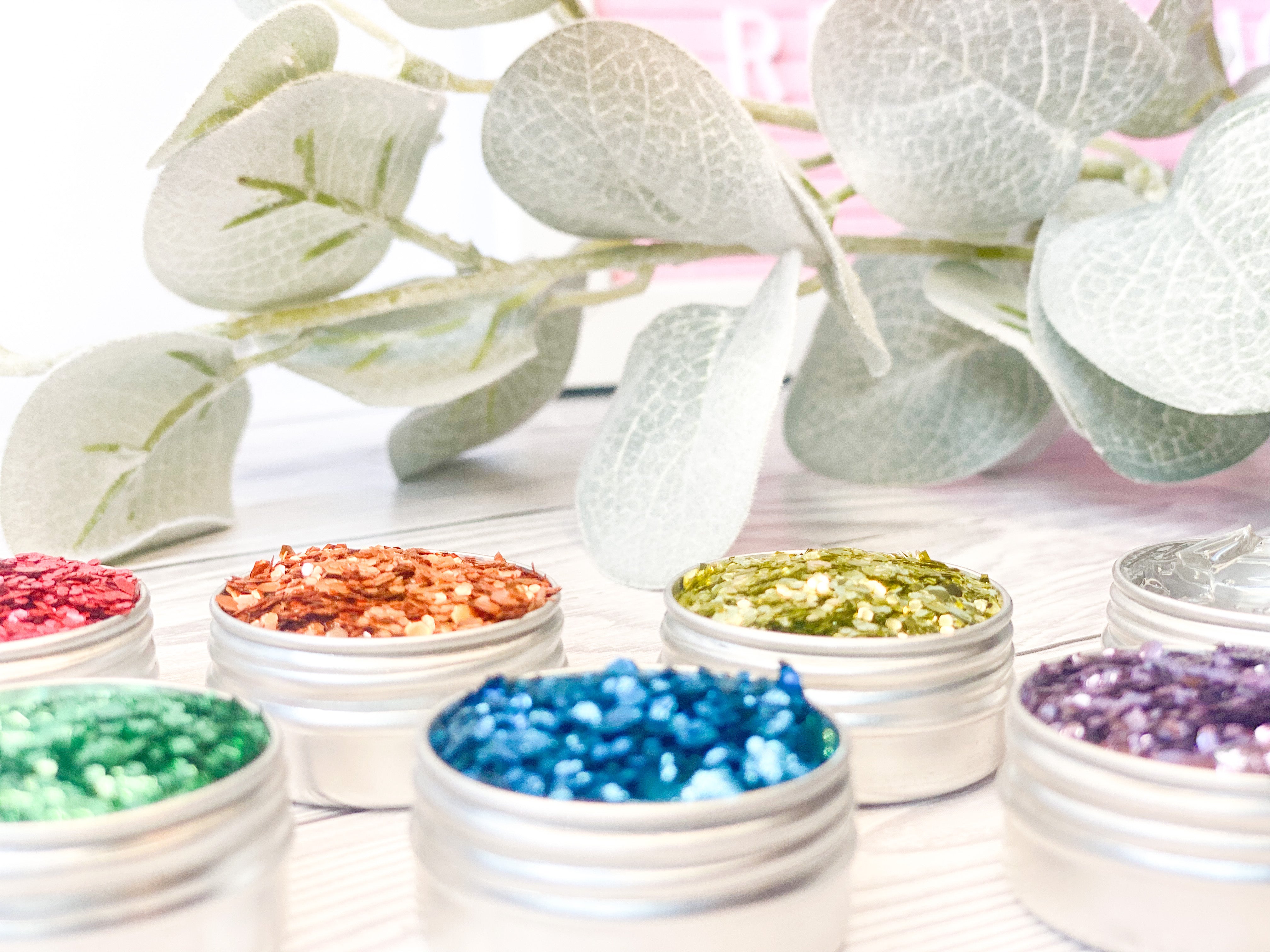 Bright coloured glitters in aluminium pots with a eucalyptus branch in the background