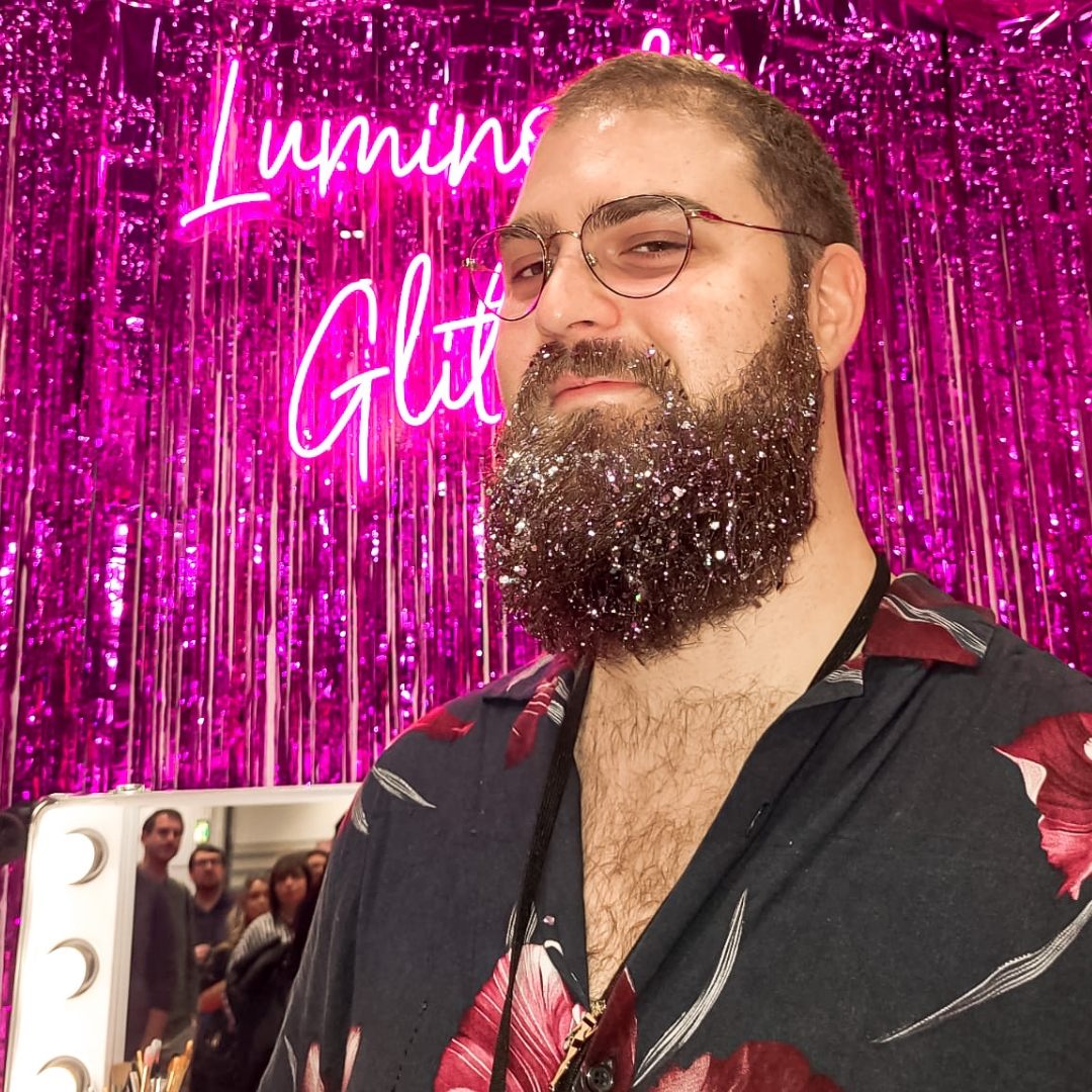 Glitter Beard at Ru Paul's drag con uk 2023 with our neon pink luminosity glitter sign in the background