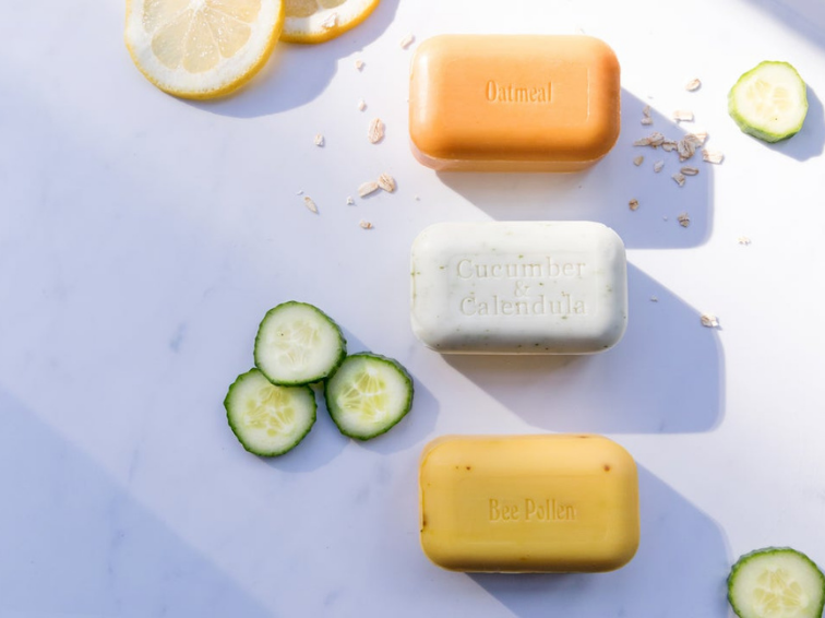 Bars of soap on a marble background surrounded by cucumber and orange pieces