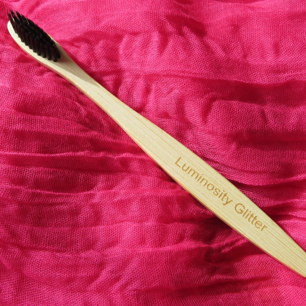 a bamboo toothbrush with black bristles for applying eco glitter to your hair and beard