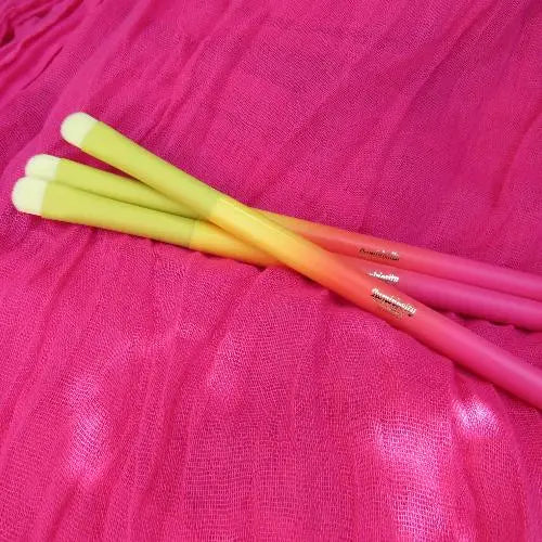 Concealer brush in ombre pink, orange and yellow for applying cosmetic glitter.