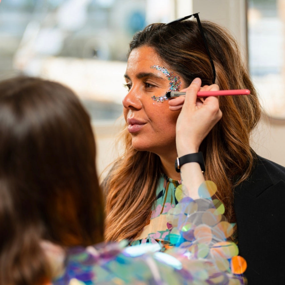 glitter artist applying face glitter in the shape of a crescent moon.