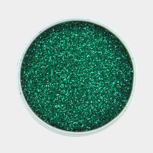 Green glitter in a small round container on a light gray background