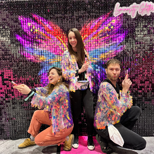 Luminosity Glitter artists infront of the butterfly sequin wall backdrop.