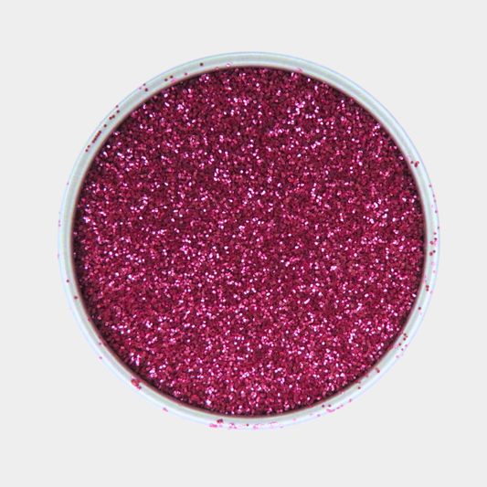 Pink glitter in a small round container on a light gray background