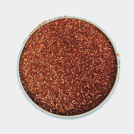 Copper-colored glitter in a small container on a light gray background