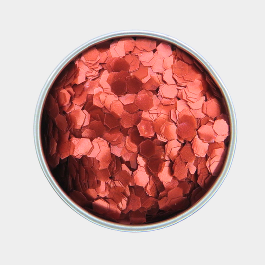 Round container filled with red hexagonal glitter on a light gray background