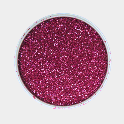 Pink glitter in a small round container on a light gray background