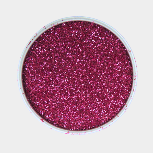 Pink glitter in a small round container on a light gray background
