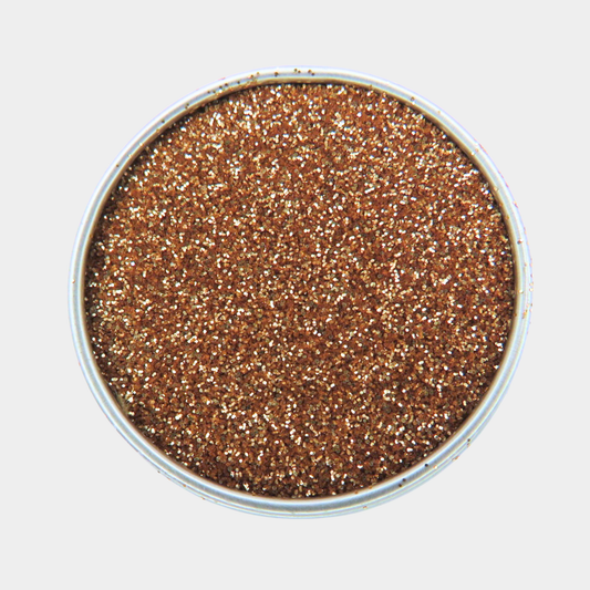 Metallic glittery powder in a round container on a light gray background