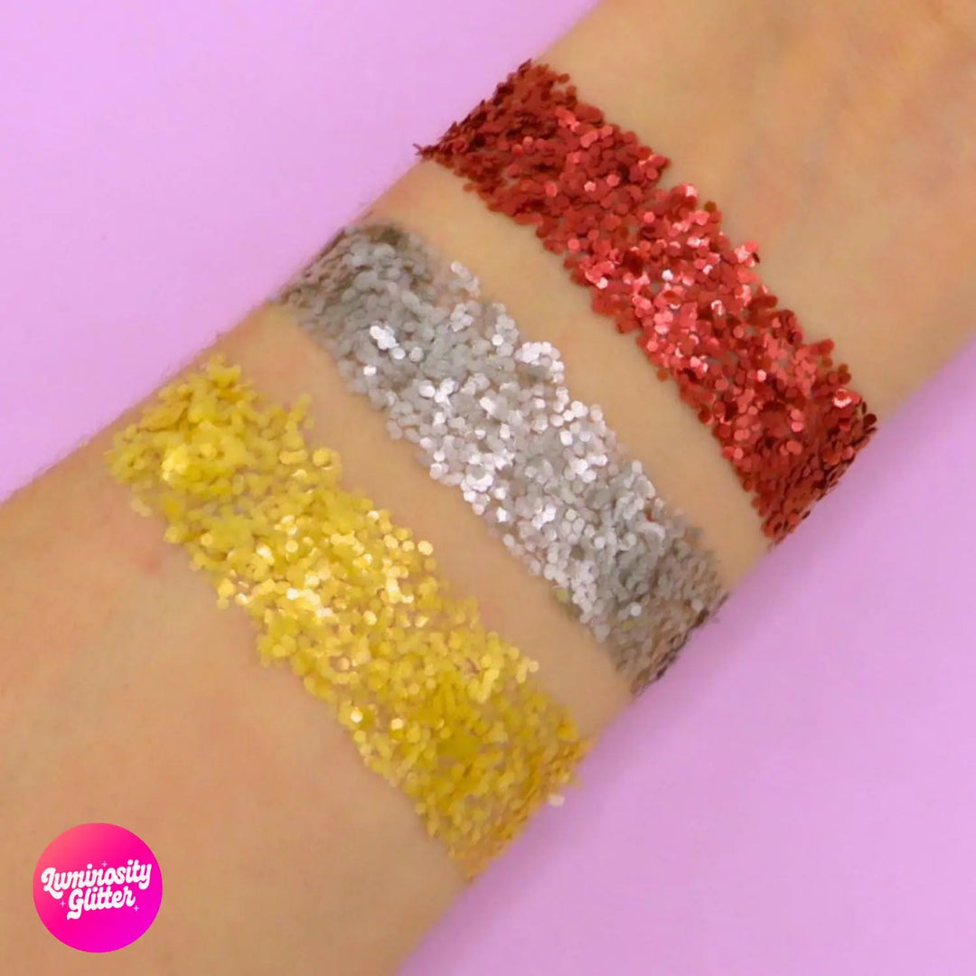 Shimmer and sleigh pure bioglitter swatch on the arm of pure red, pure silver and pure honey gold chunky glitter.