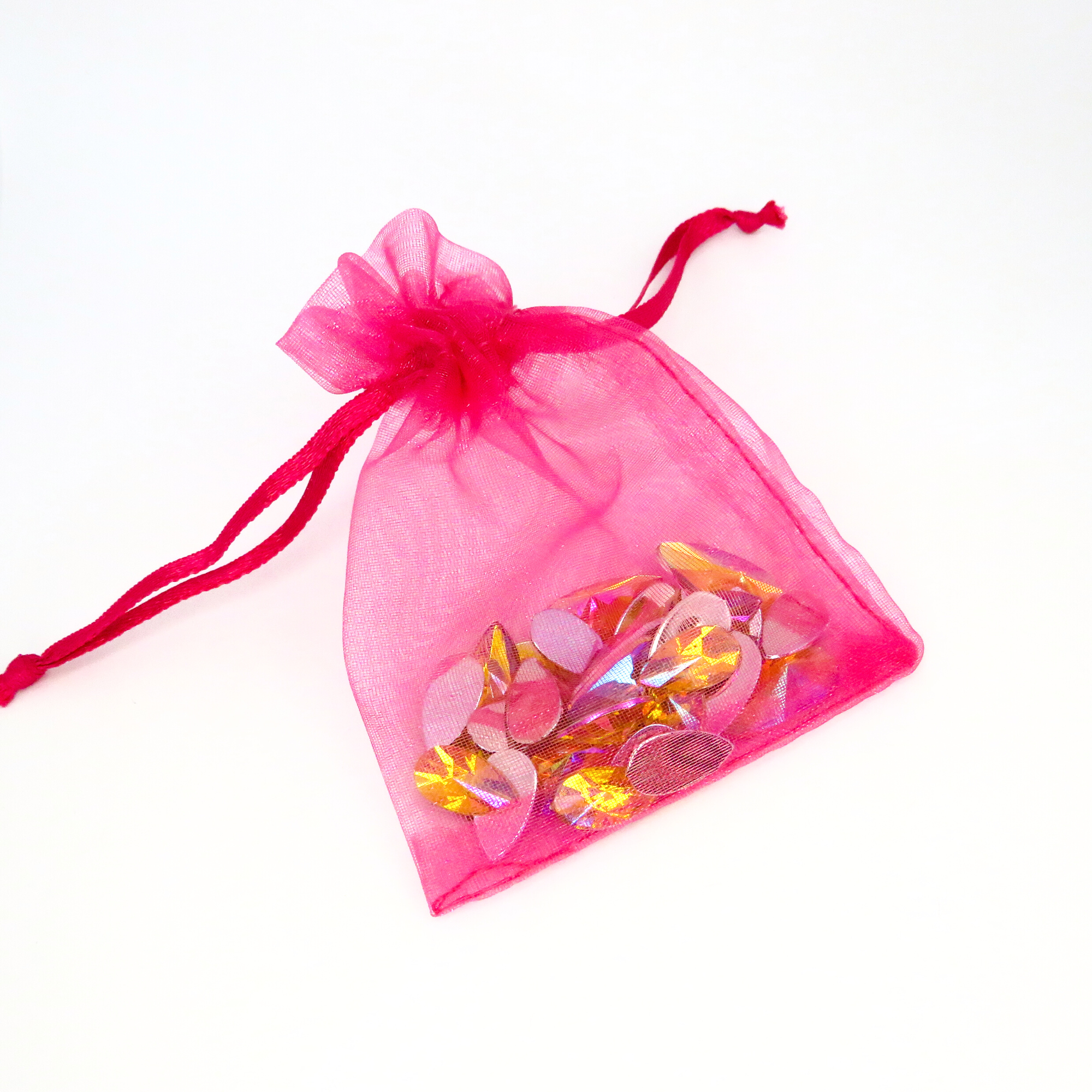 A hot pink organza bag filled with citrine face gems by Luminosity Glitter