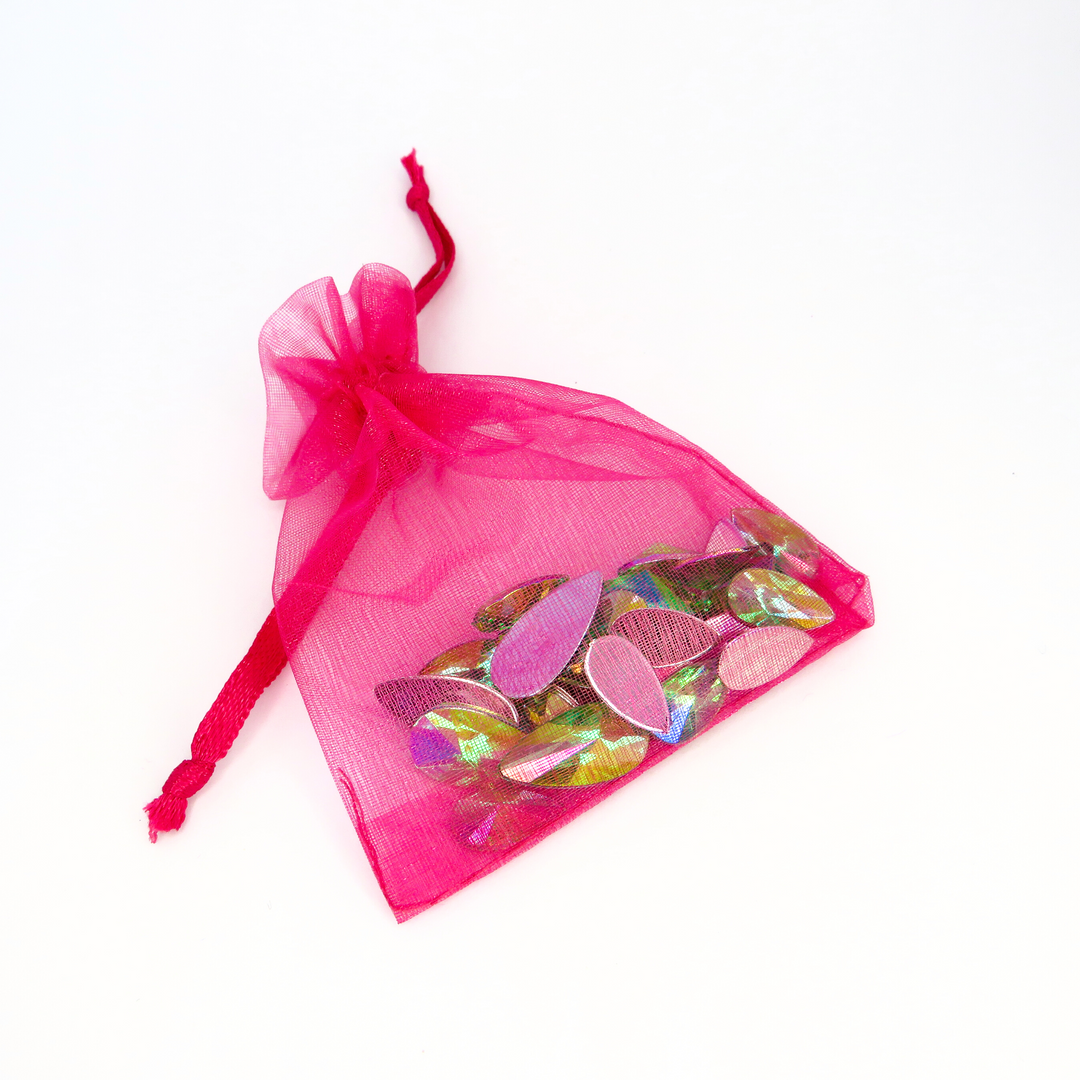 A hot pink organza bag filled with lime soda green reusable face gems for festivals and makeup by Luminosity Glitter