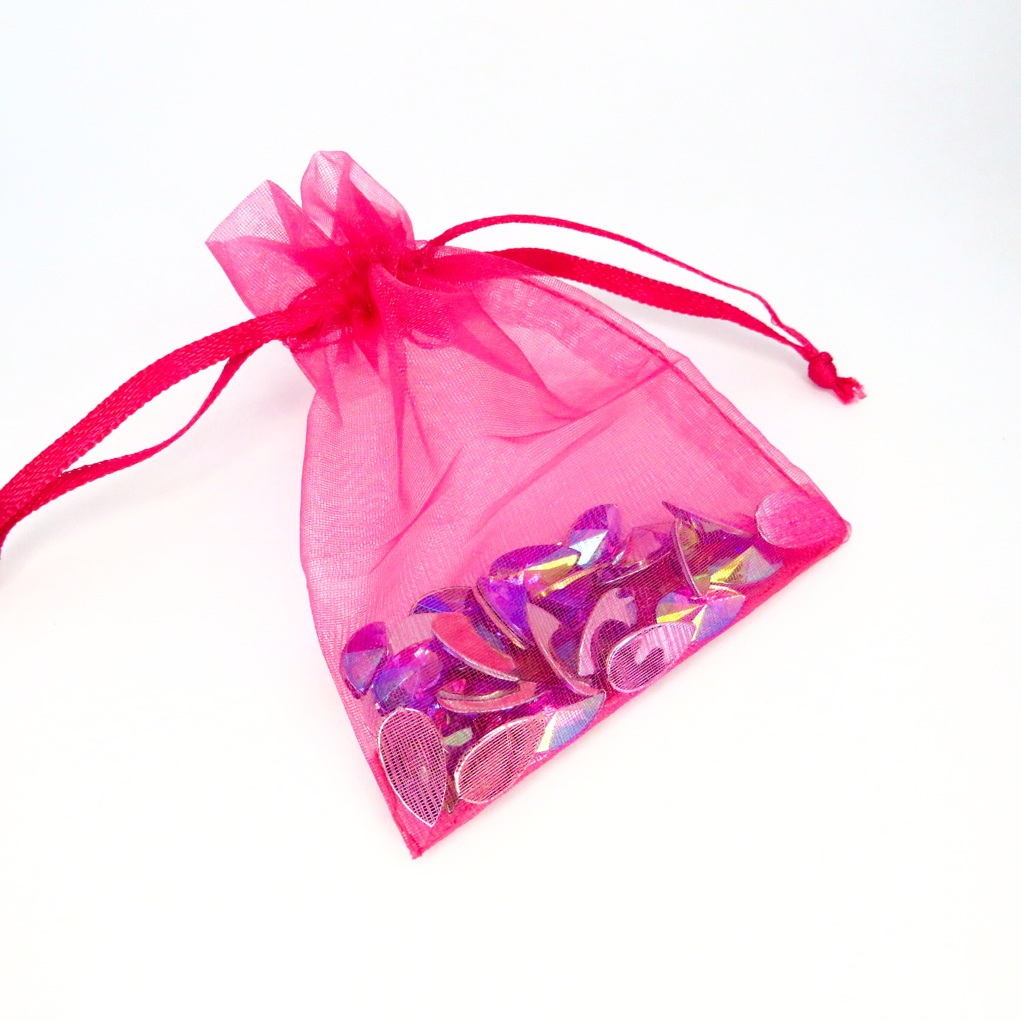 A pink organza drawstring bag filled with purple reusable face and body gems