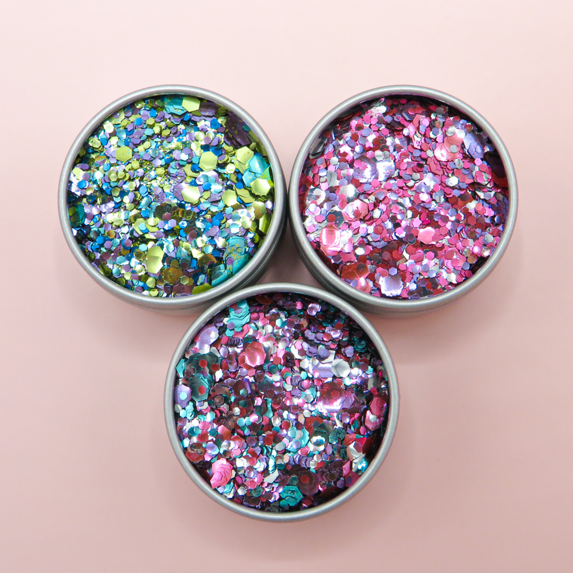 Trio of biodegradable cosmetic glitter with pinks, silvers and purples.