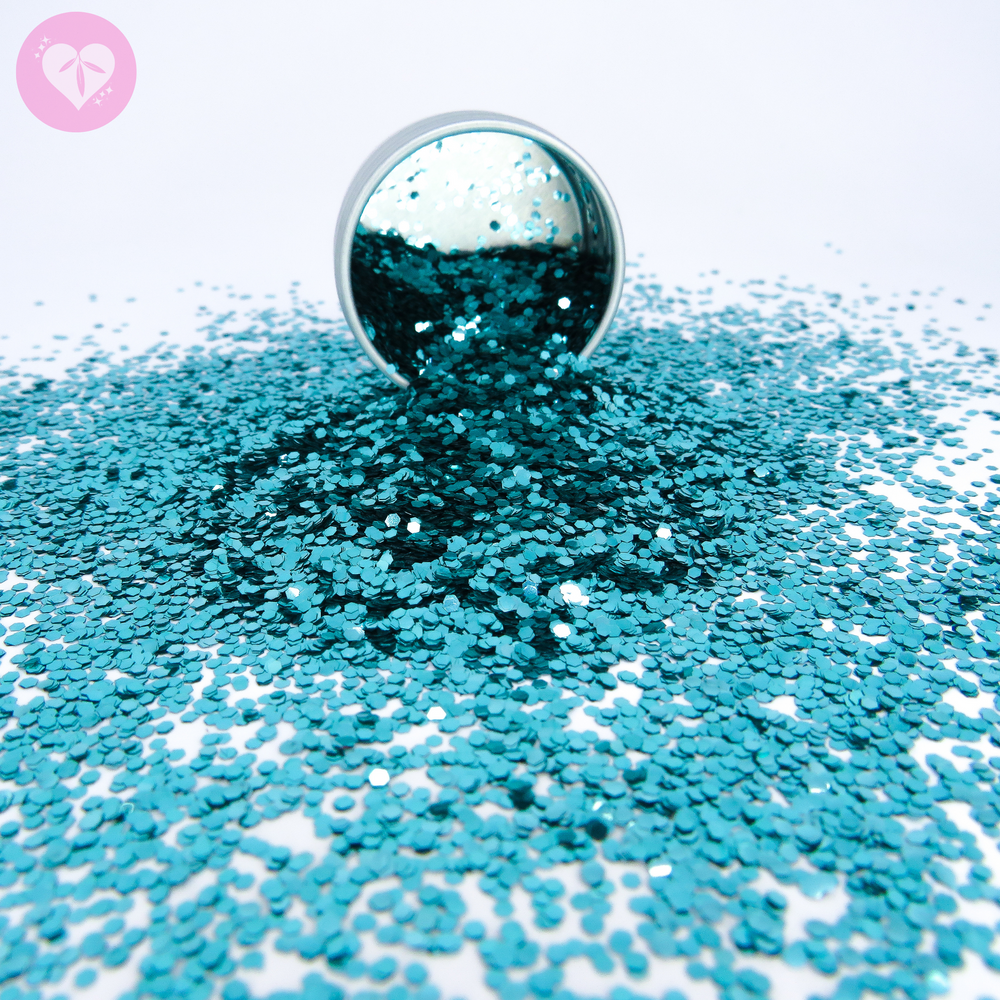 Chunky turquoise eco friendly cosmetic glitter in hexagonal shape. The glitter is spilling out of an aluminium pot